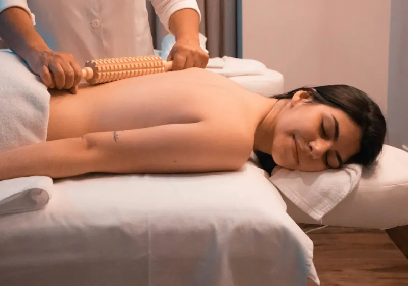 Terapeuta realizando maderoterapia con rodillo de madera en la espalda
