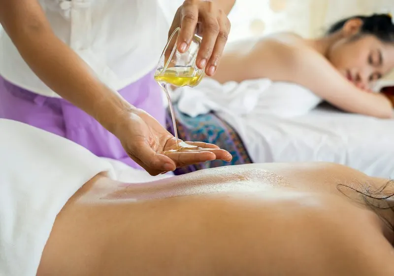 Terapeuta aplicando aceite tibio en la espalda durante un masaje relajante